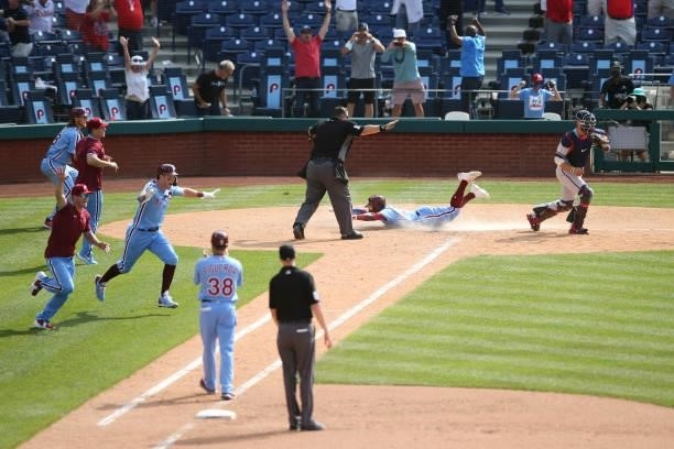 Odúbel Herrera of the Philadelphia Phillies scores the winning run as Philadelphia Phillies players rush the field during the game between the...