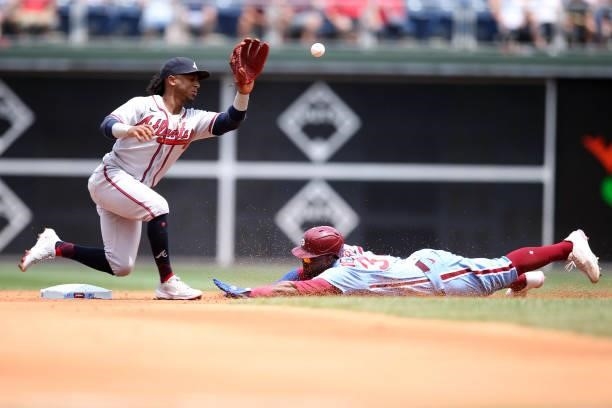 Ozzie Albies of the Atlanta Braves tries to catch the ball as Odúbel Herrera of the Philadelphia Phillies successfully steals second base during the...