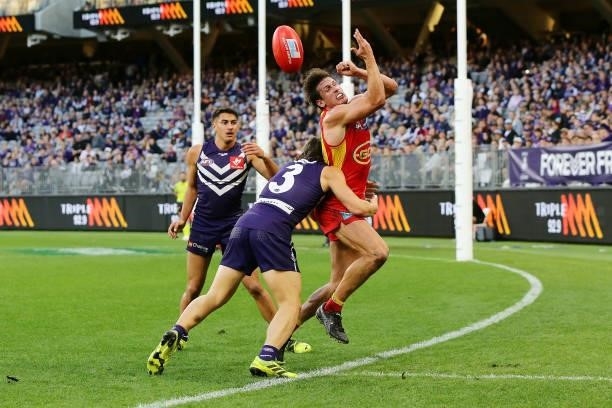 David Swallow of the Suns handpasses the ball under pressure from Caleb Serong of the Dockers during the 2021 AFL Round 13 match between the...