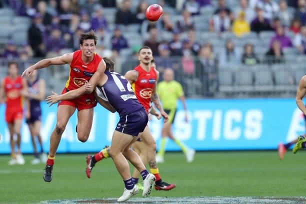 David Swallow of the Suns handpasses the ball under pressure from Mitch Crowden of the Dockers during the 2021 AFL Round 13 match between the...