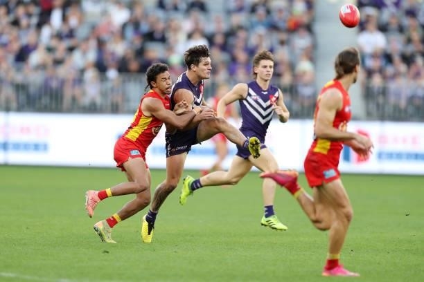 Lachie Schultz of the Dockers kicks the ball under pressure from Touk Miller of the Suns during the 2021 AFL Round 13 match between the Fremantle...