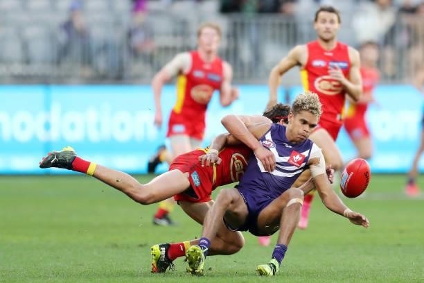 Liam Henry of the Dockers is tackled by Wil Powell of the Suns during the 2021 AFL Round 13 match between the Fremantle Dockers and the Gold Coast...