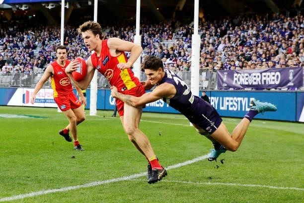 Charlie Ballard of the Suns is tackled by Rory Lobb of the Dockers during the 2021 AFL Round 13 match between the Fremantle Dockers and the Gold...