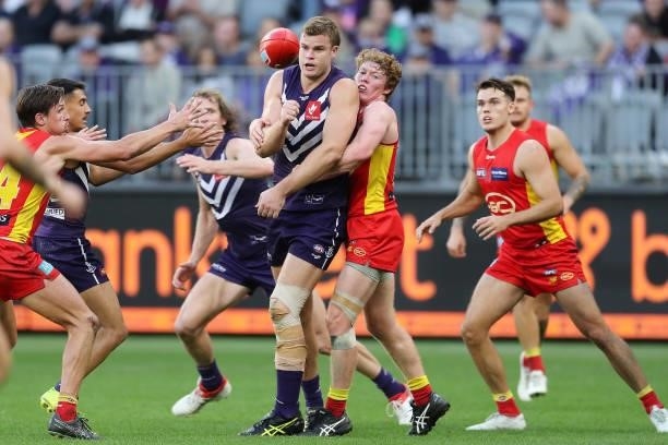 Sean Darcy of the Dockers handpasses the ball under pressure from Matt Rowell during the 2021 AFL Round 13 match between the Fremantle Dockers and...