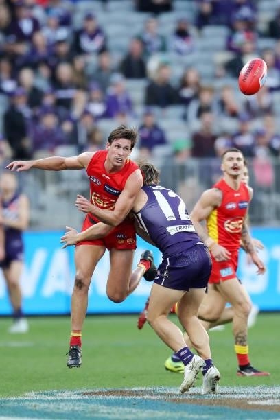 David Swallow of the Suns handpasses the ball under pressure from Mitch Crowden of the Dockers during the 2021 AFL Round 13 match between the...