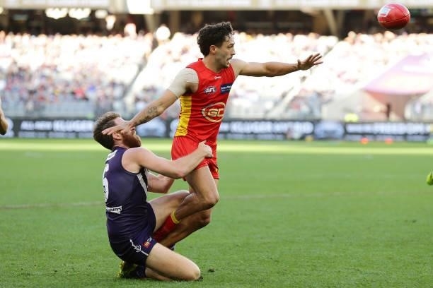Izak Rankine of the Suns is tackled by Reece Conca of the Dockers during the 2021 AFL Round 13 match between the Fremantle Dockers and the Gold Coast...