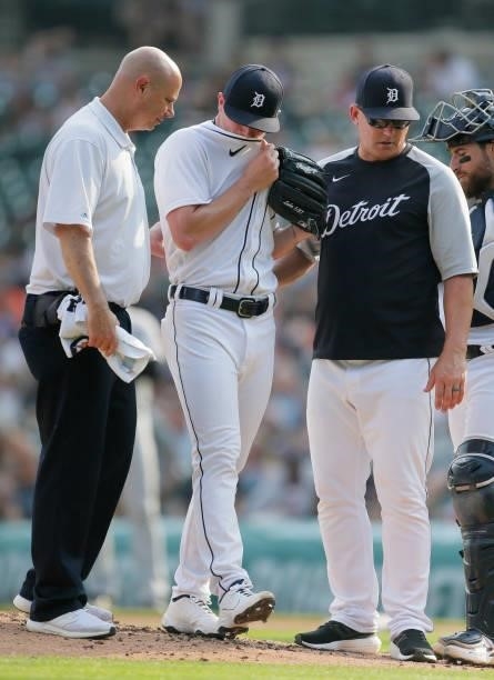 Relief pitcher Beau Burrows of the Detroit Tigers is directed off the field by assistant trainer Chris McDonald, left, and manager A.J. Hinch after...