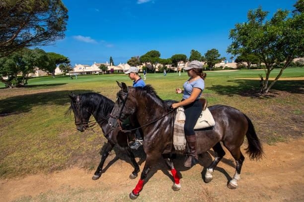 People ride by on horses as players play on the first hole during Day Four of the Challenge de Cadiz at Iberostar Real Club de Golf Novo Sancti Petri...