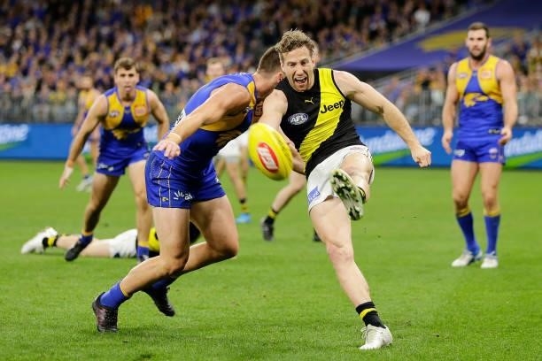 Kane Lambert of the Tigers kicks the ball under pressure from Elliot Yeo of the Eagles during the 2021 AFL Round 13 match between the West Coast...