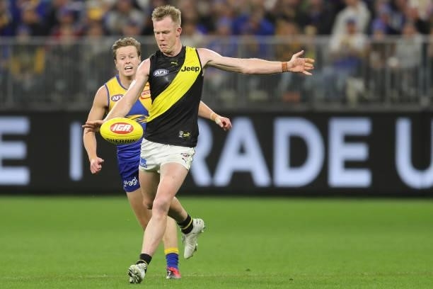 Jack Riewoldt of the Tigers kicks the ball under pressure from Jackson Nelson of the Eagles during the 2021 AFL Round 13 match between the West Coast...