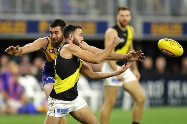 Marlion Pickett of the Tigers handpasses the ball under pressure from Josh J. Kennedy of the Eagles during the 2021 AFL Round 13 match between the...