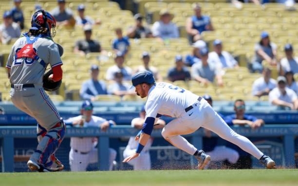 Gavin Lux of the Los Angeles Dodgers is caught in a rundown between third base and home plate and tagged out by catcher Jonah Heim of the Texas...