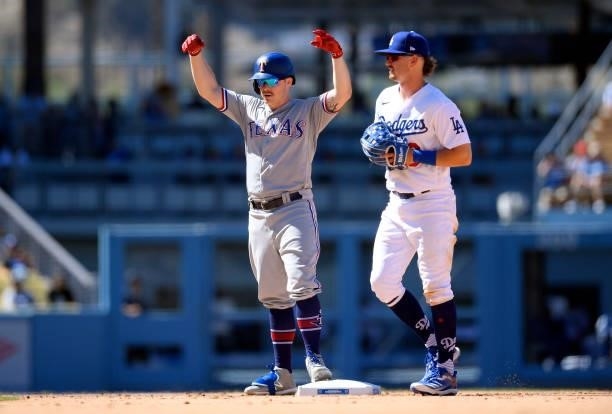 Brock Holt of the Texas Rangers celebrate after hitting a double against relief pitcher Phil Bickford with Zach McKinstry of the Los Angeles Dodgers...