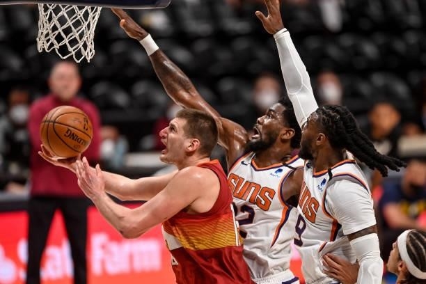 Nikola Jokic of the Denver Nuggets drives to the net under coverage by Jae Crowder and Deandre Ayton of the Phoenix Suns in Game Four of the Western...