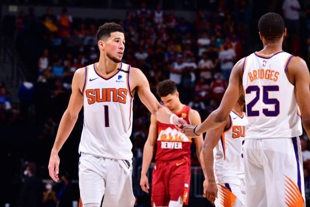 Devin Booker of the Phoenix Suns hi-fives Mikal Bridges during Round 2, Game 4 of the 2021 NBA Playoffs on June 13, 2021 at the Ball Arena in Denver,...
