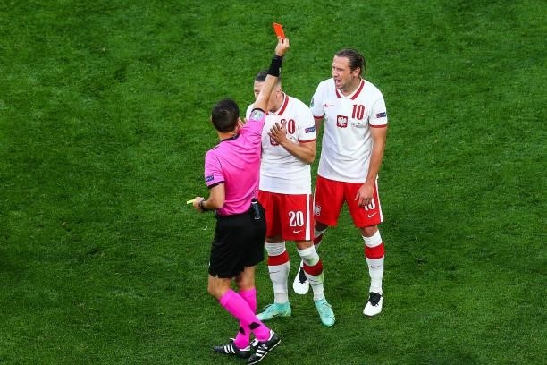 Grzegorz Krychowiak of Poland is shown a red card by Match Referee, Ovidiu Hategan as Piotr Zielinski of Poland protests during the UEFA EURO 2020...