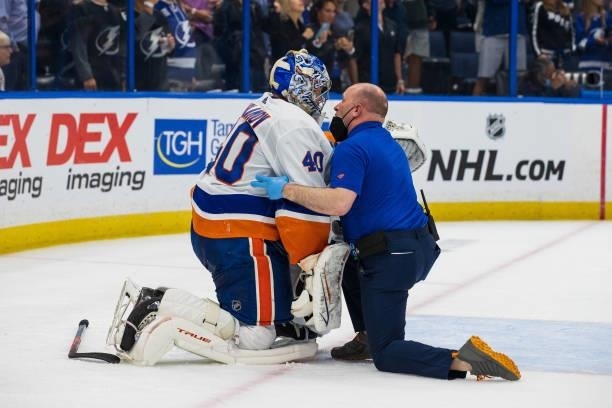 Goalie Semyon Varlamov of the New York Islanders is checked on by a member of the training staff after getting hit by Brayden Point of the Tampa Bay...