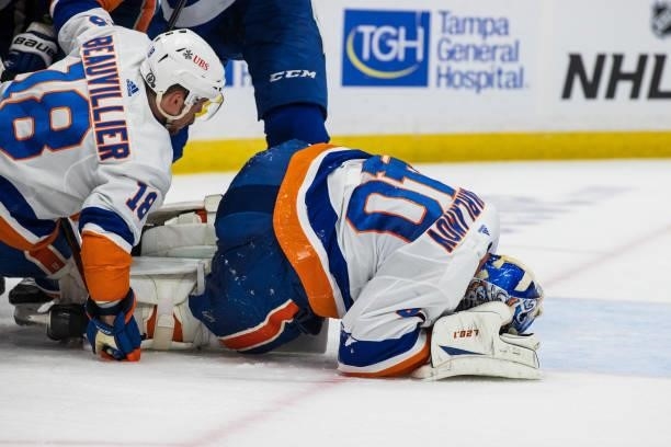 Goalie Semyon Varlamov of the New York Islanders covers his head after getting hit by Brayden Point of the Tampa Bay Lightning during the first...