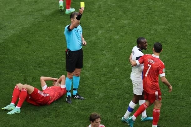 Dutch referee Danny Makkelie shows a yellow card to Finland's midfielder Glen Kamara for a challange on Russia's defender Mario Fernandes during the...