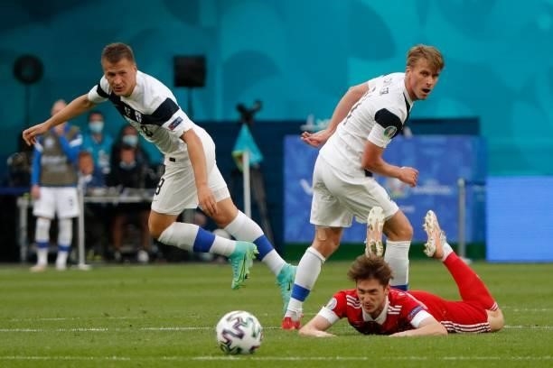 Russia's forward Aleksey Miranchuk goes down after he was challangd by Finland's midfielder Rasmus Schuller and Finland's midfielder Robin Lod during...
