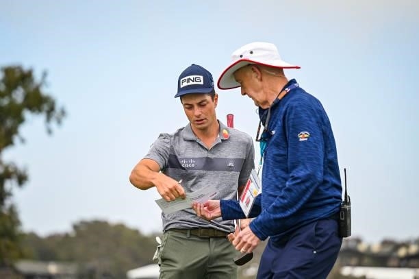 Viktor Hovland reviews his scorecard in front of USGA Rules Official Phil Miller after withdrawing from the tournament on the first hole during the...