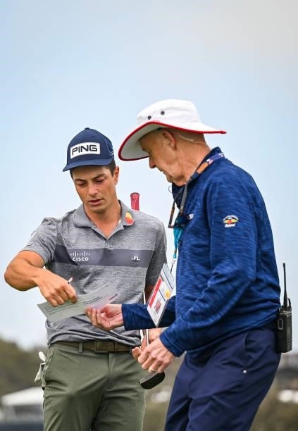 Viktor Hovland reviews his scorecard in front of USGA Rules Official Phil Miller after withdrawing from the tournament on the first hole during the...