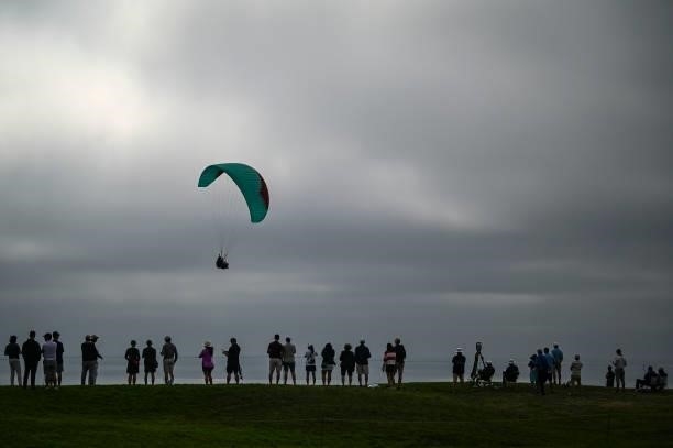 Fans watch play on the fourth hole as a paraglider flies by during the second round of the 121st U.S. Open on the South Course at Torrey Pines Golf...