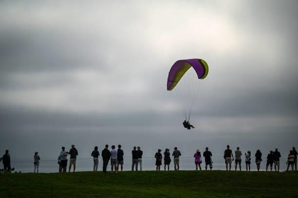 Fans watch play on the fourth hole as a paraglider flies by during the second round of the 121st U.S. Open on the South Course at Torrey Pines Golf...