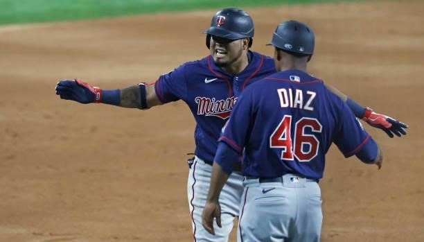 Luis Arraez and third base coach Tony Diaz of the Minnesota Twins react after Arraez batted in the winning run against the Texas Rangers during the...