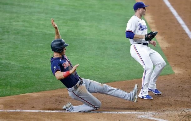 Max Kepler of the Minnesota Twins scores on a wild pitch as John King of the Texas Rangers looks on during the seventh inning at Globe Life Field on...