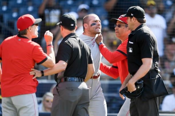 Joey Votto and manager David Bell of the Cincinnati Reds yell at umpire Ryan Additon after a call during the first inning of a baseball game against...