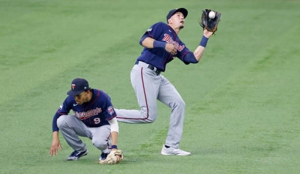 Andrelton Simmons of the Minnesota Twins gets low to the ground as teammate Trevor Larnach catches a fly ball off the bat of Eli White of the Texas...