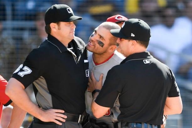 Joey Votto of the Cincinnati Reds is held back by umpire Jim Reynolds as he yells at umpire Ryan Additon after a call during the first inning of a...