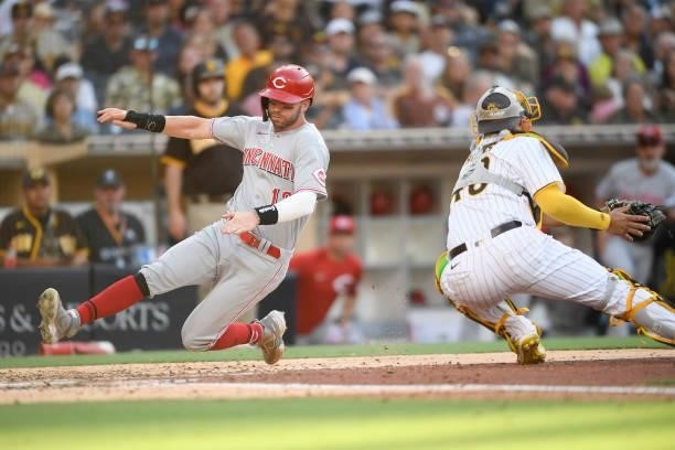 Tyler Naquin of the Cincinnati Reds scores ahead of the tag of Webster Rivas of the San Diego Padres during the fifth inning of a baseball game at...