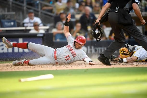 Tyler Naquin of the Cincinnati Reds scores ahead of the tag of Webster Rivas of the San Diego Padres during the fifth inning of a baseball game at...