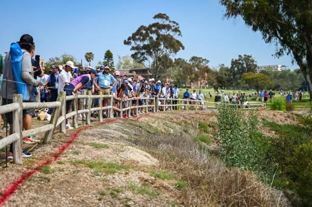 Rory McIlroy of Northern Ireland looks for his ball in the barranca to the left of the 15th hole fairway before taking a penalty drop during the...