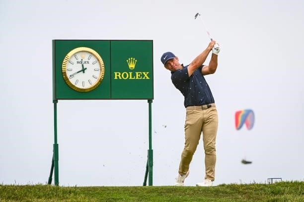Paul Casey of England plays his shot from the 16th tee next to a Rolex clock as a paraglider flies by during the third round of the 121st U.S. Open...