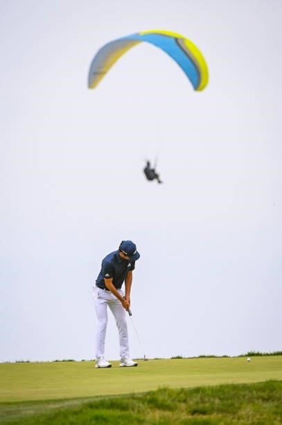Joaquin Niemann of Chile putts on the 12th hole green as a paraglider flies by during the third round of the 121st U.S. Open on the South Course at...