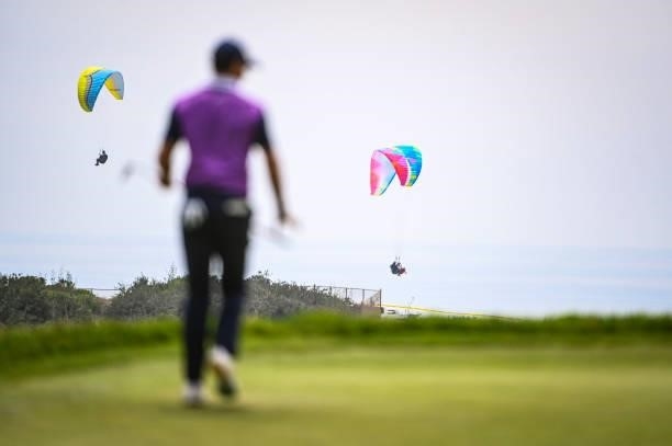Paragliders fly by as Rory McIlroy of Northern Ireland plays the 14th hole during the third round of the 121st U.S. Open on the South Course at...