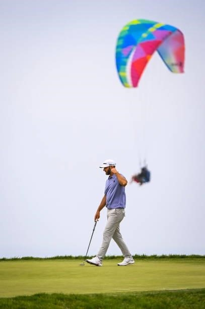 Dustin Johnson reads his putt on the 12th hole green as a paraglider flies by during the third round of the 121st U.S. Open on the South Course at...