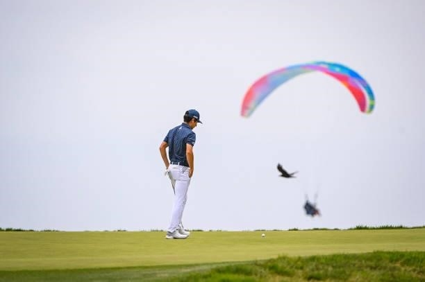 Joaquin Niemann of Chile reads his putt on the 12th hole green as a paraglider and a bird fly by during the third round of the 121st U.S. Open on the...