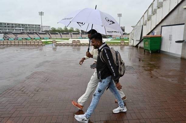 Indian fans walk in the rain on the fourth day of the ICC World Test Championship Final between New Zealand and India at the Ageas Bowl in...