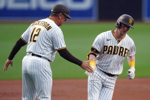 Third base coach Bobby Dickerson of the San Diego Padres high fives Jake Cronenworth after Cronenworth hit a home run during the game between the Los...