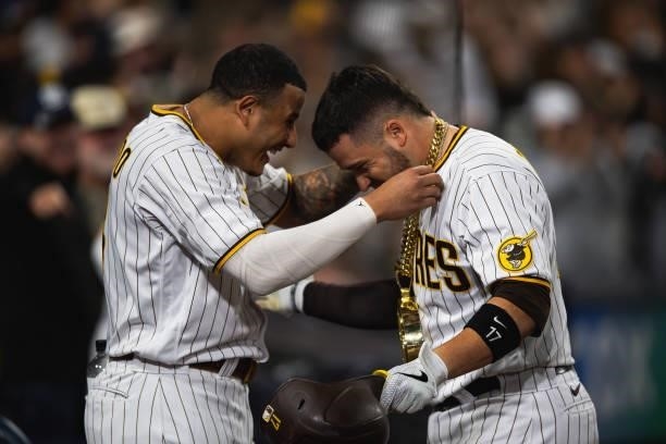 Manny Machado of the San Diego Padres places the 'swag chain' on Victor Caratini after hitting a home run in the seventh inning against the Los...