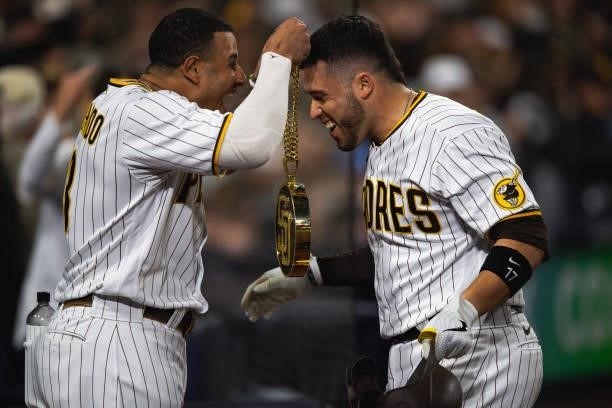 Manny Machado of the San Diego Padres places the 'swag chain' on Victor Caratini after hitting a home run in the seventh inning against the Los...