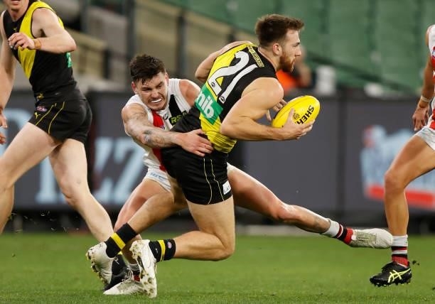 Noah Balta of the Tigers injures his leg as Josh Battle of the Saints tackles him during the 2021 AFL Round 15 match between the Richmond Tigers and...