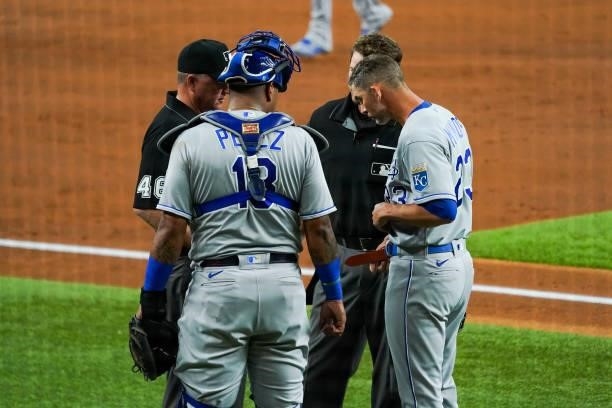 Umpires check the belt and glove of Mike Minor of the Kansas City Royals for foreign substances in the 2nd inning of the game against the Texas...