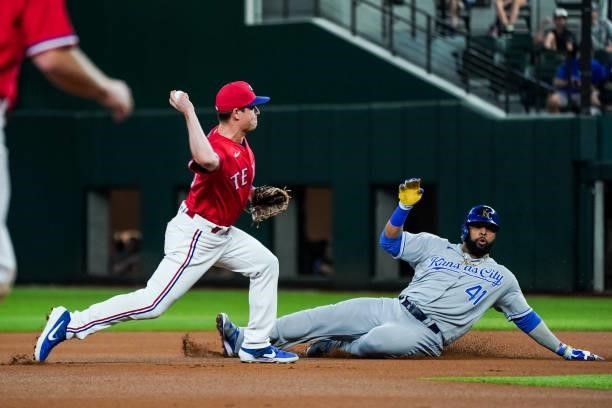 Nick Solak of the Texas Rangers throws to first to complete the double play whilst Carlos Santana of the Kansas City Royals attempts to slide to...