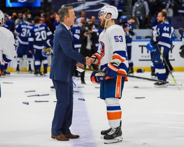 Head Coach Jon Cooper of the Tampa Bay Lightning celebrates the game and series win and shakes hands with Casey Cizikas of the New York Islanders in...