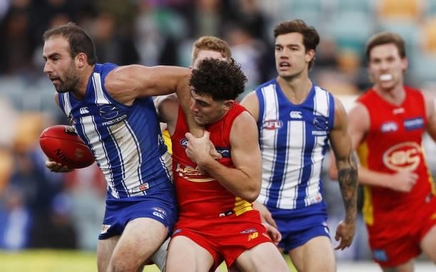 Ben Cunnington of the Kangaroos is tackled by Sam Flanders of the Suns during the 2021 AFL Round 15 match between the North Melbourne Kangaroos and...